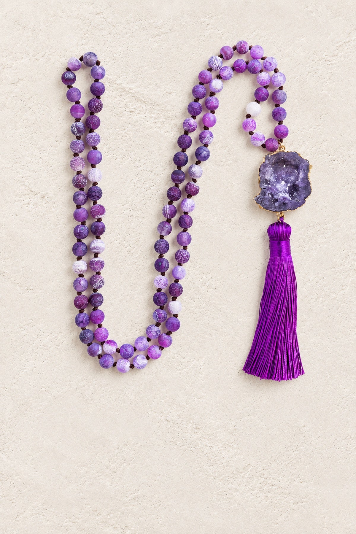 
                  
                    Purple Agate Slice Tassel Necklace on warm cream plaster background
                  
                