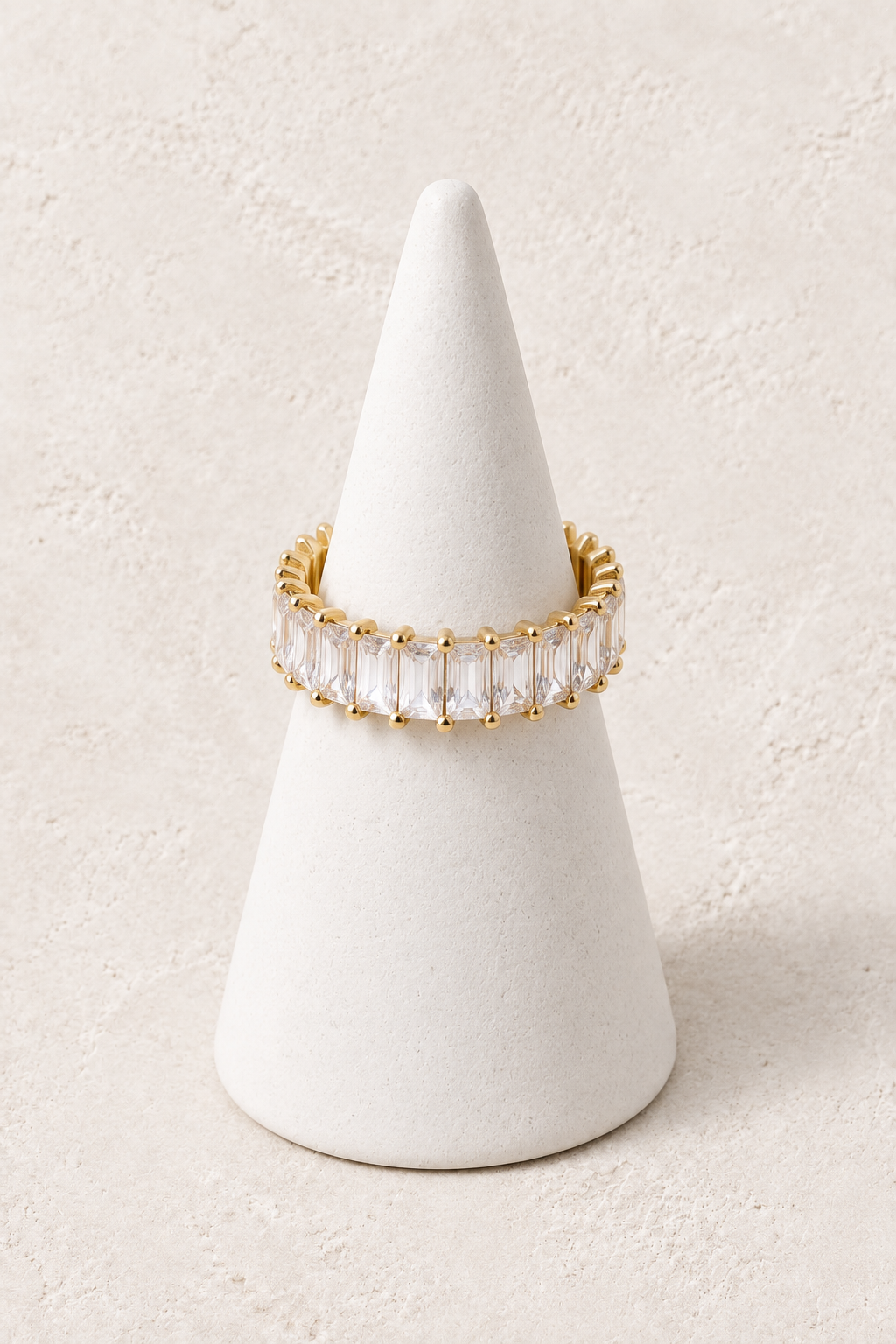 Radiance Crystal Ring on a white display cone against a warm textured background