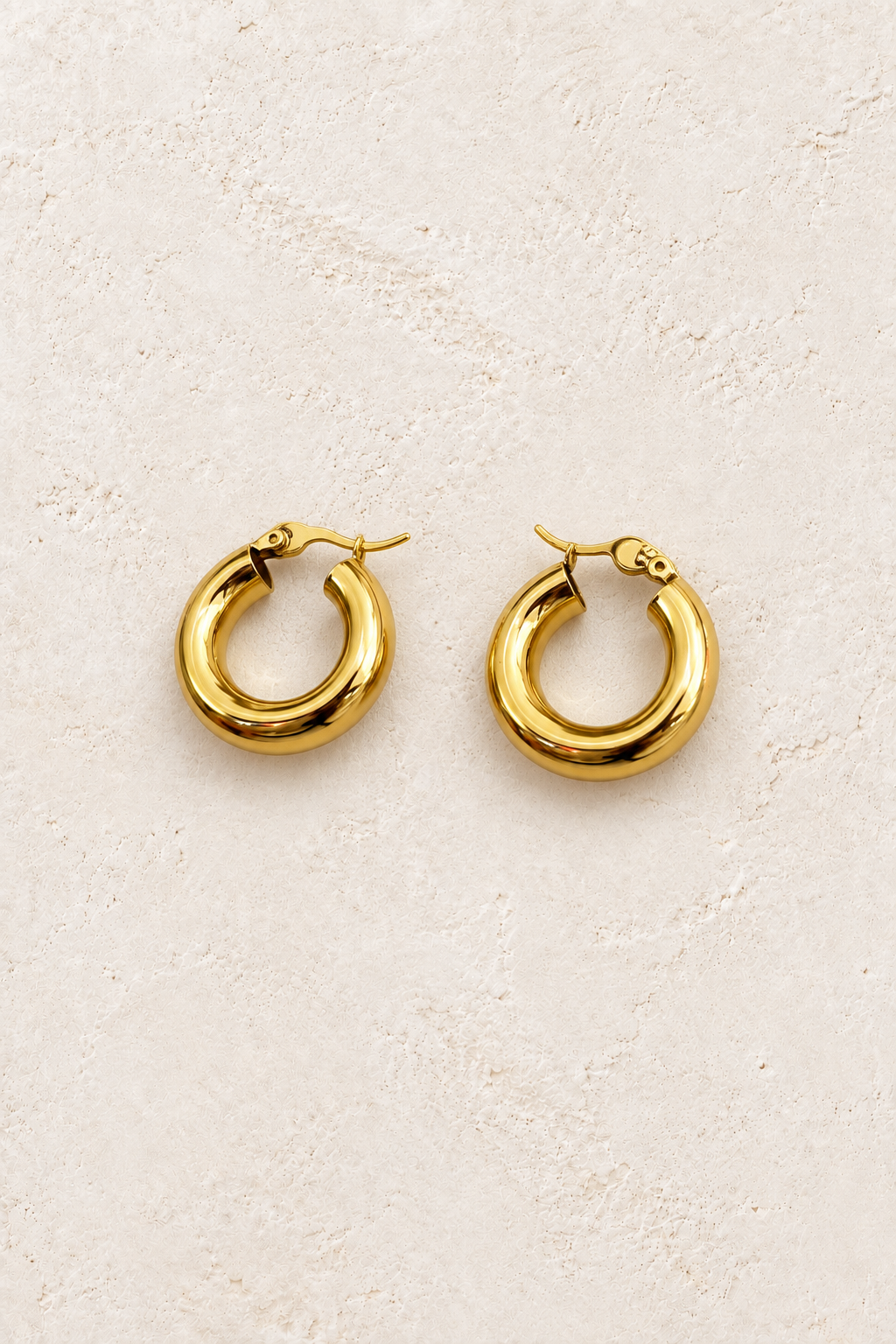 
                  
                    Romy bold gold hoops on warm ivory textured background
                  
                