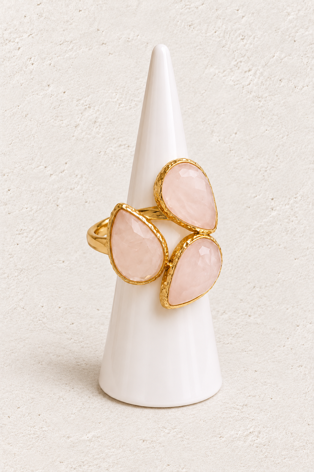 Seraphine Rose Quartz Ring on white cone against warm textured background