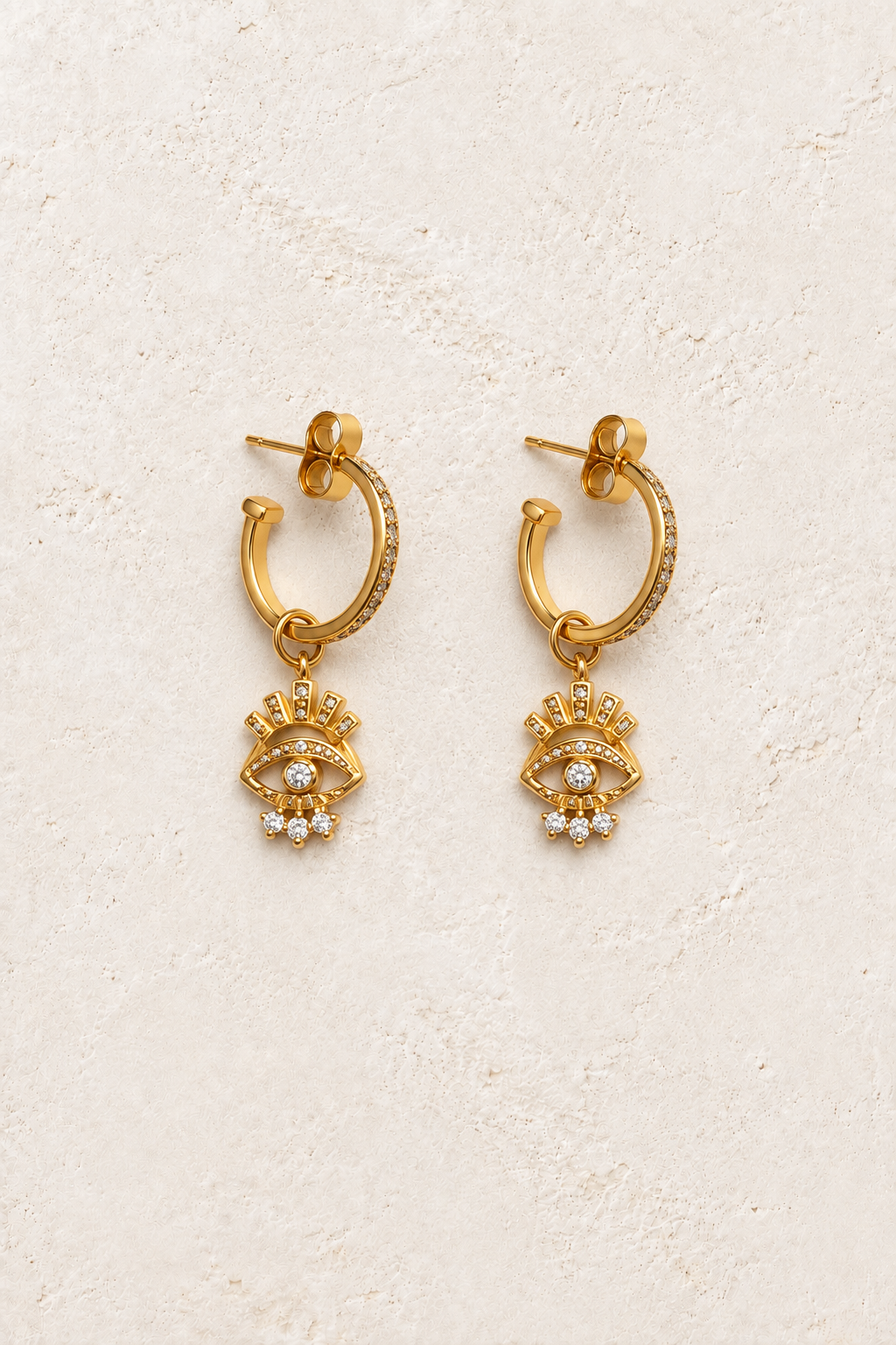 
                  
                    Savia Evil Eye Charm Hoops on warm ivory textured background
                  
                