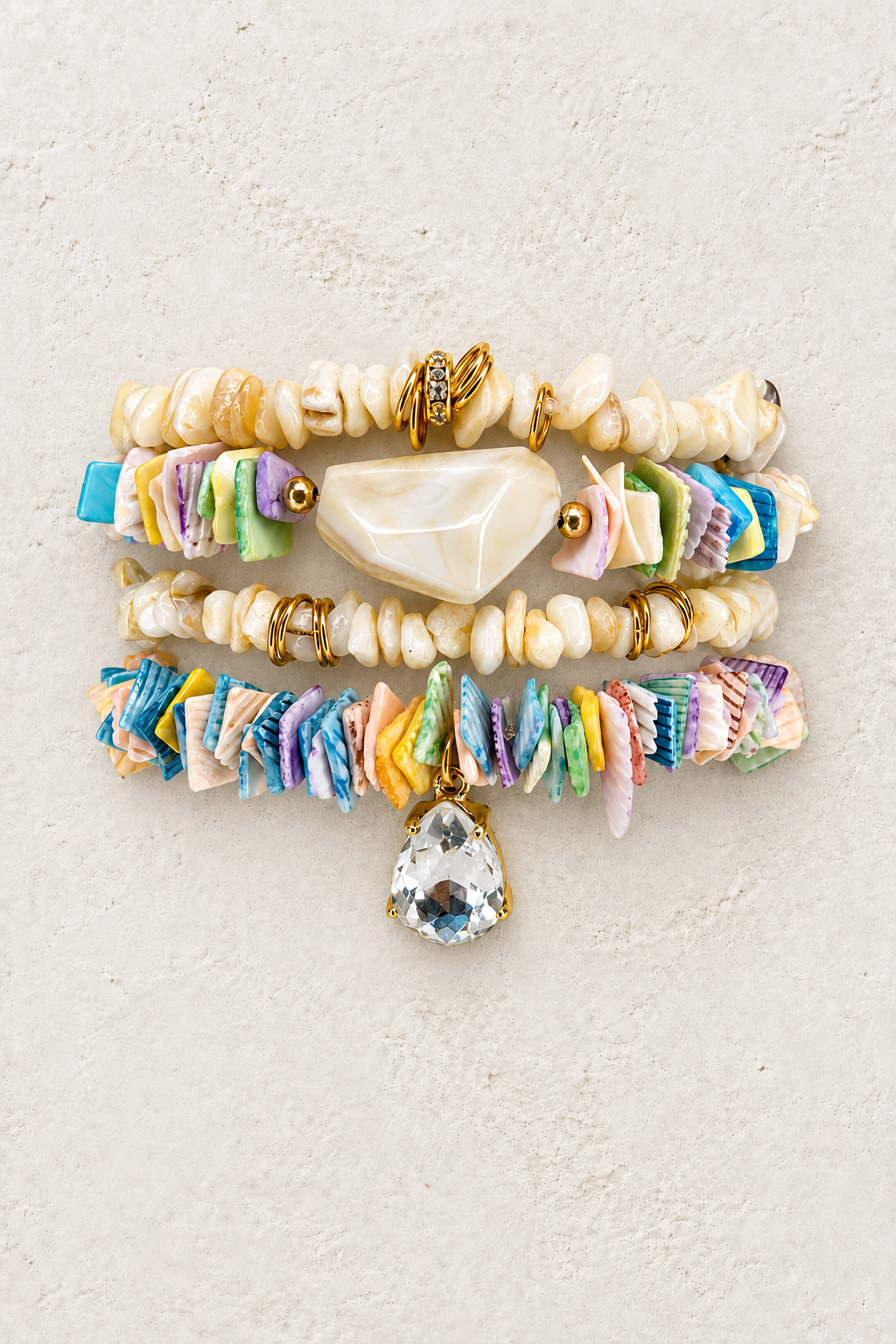 Seashell Festival 4-piece elastic bracelet stack on warm textured background