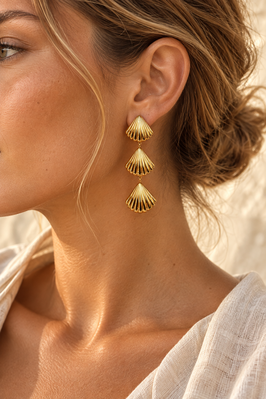 
                  
                    Model wearing Sereia gold triple shell drop earring
                  
                