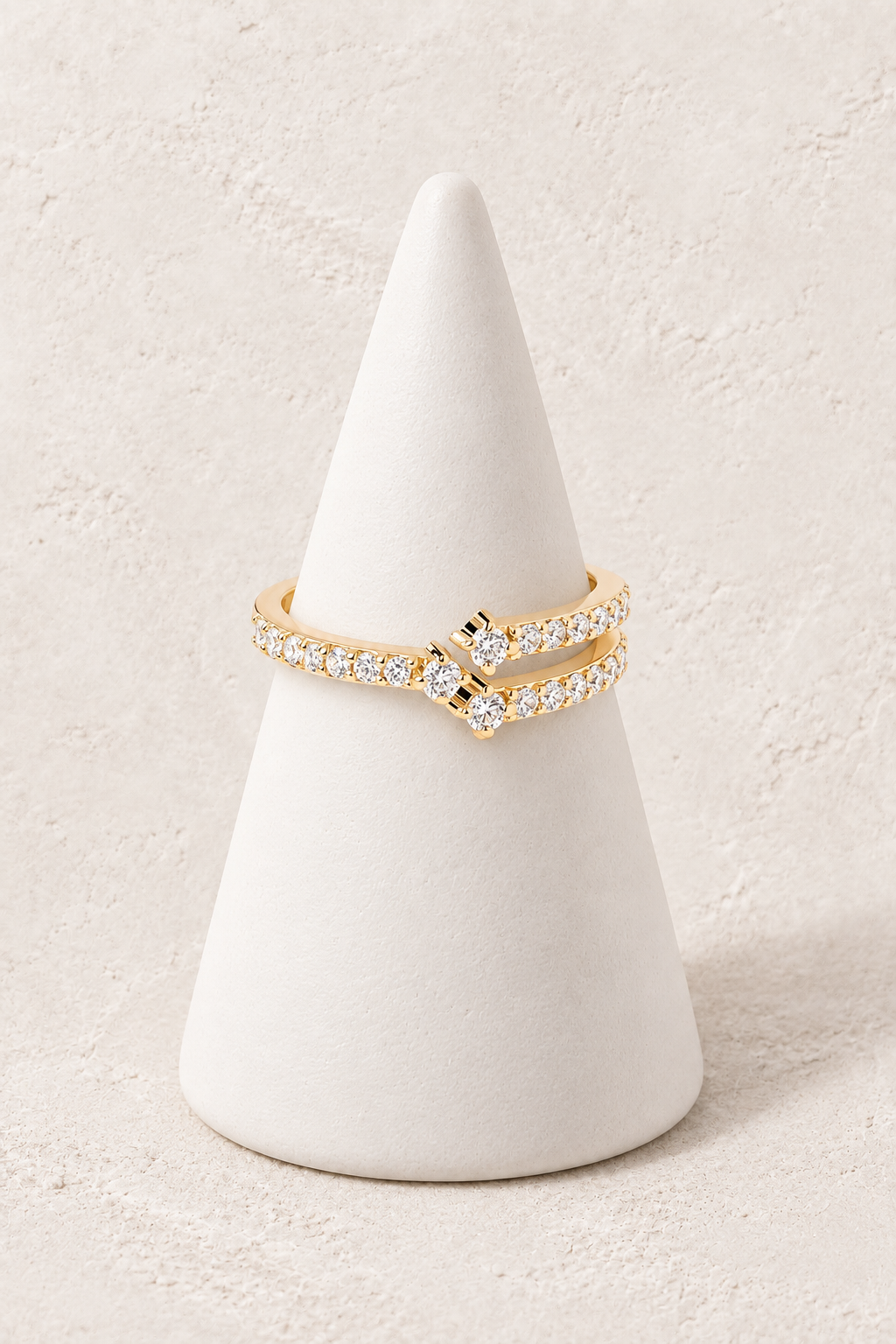 
                  
                    Sienna Crystal Crossover Ring on a white display cone against a warm textured background
                  
                