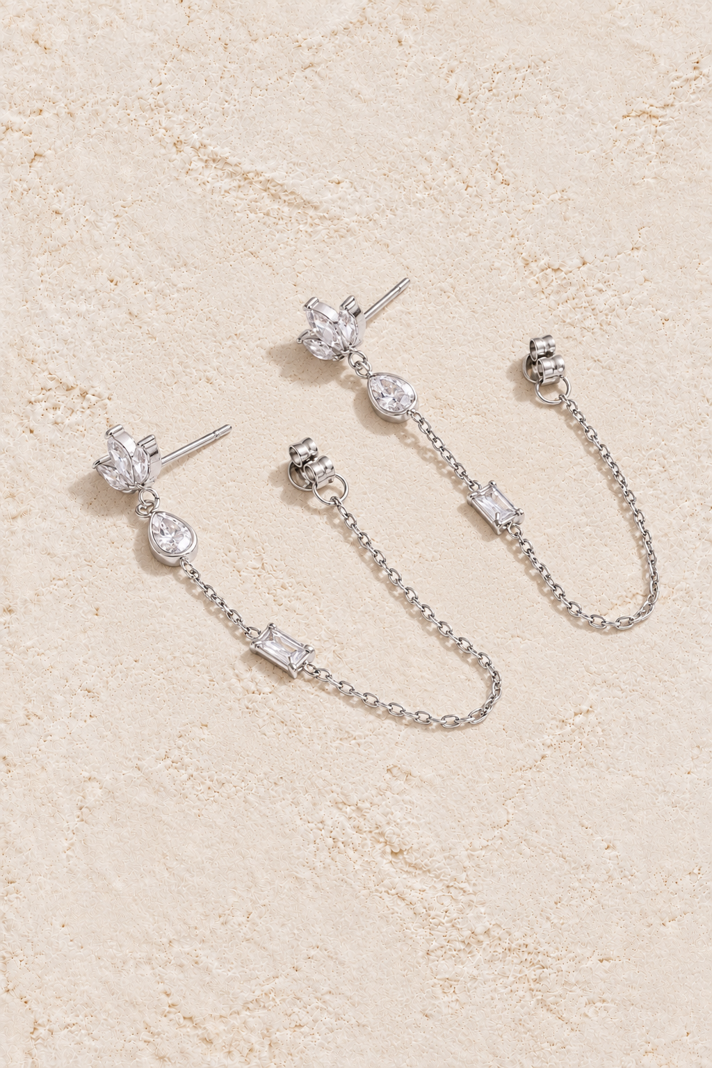 
                  
                    Silver crystal leaf loop chain earrings on cream plaster
                  
                