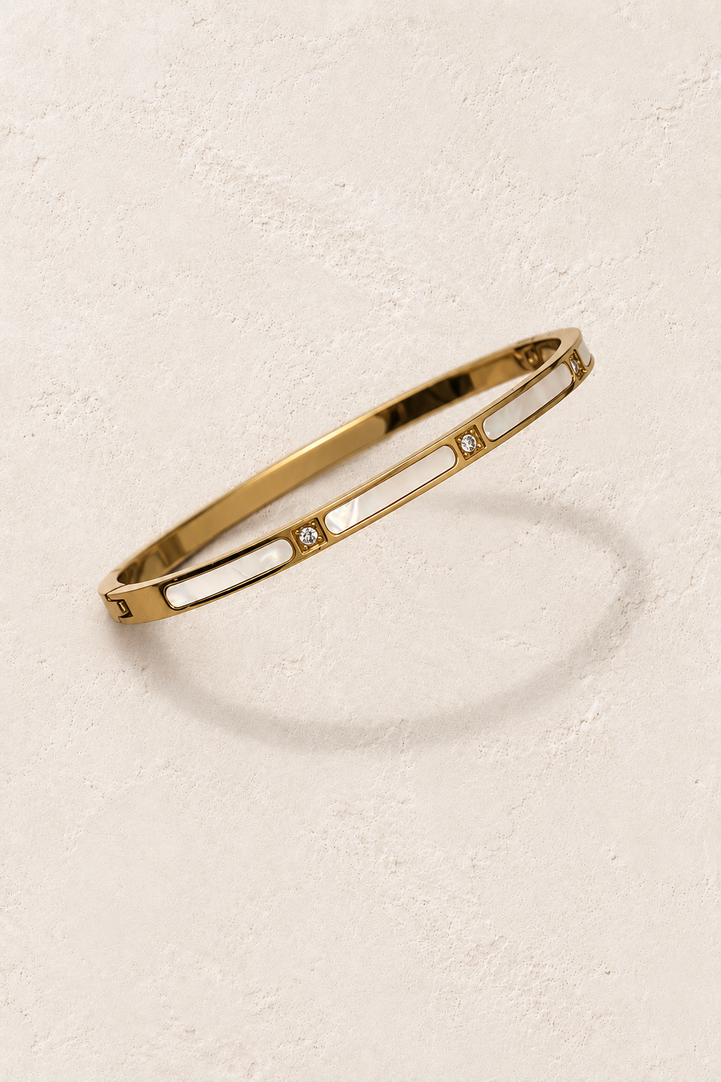 Sola Gold Pearl Shell Crystal Bangle on cream beige textured background