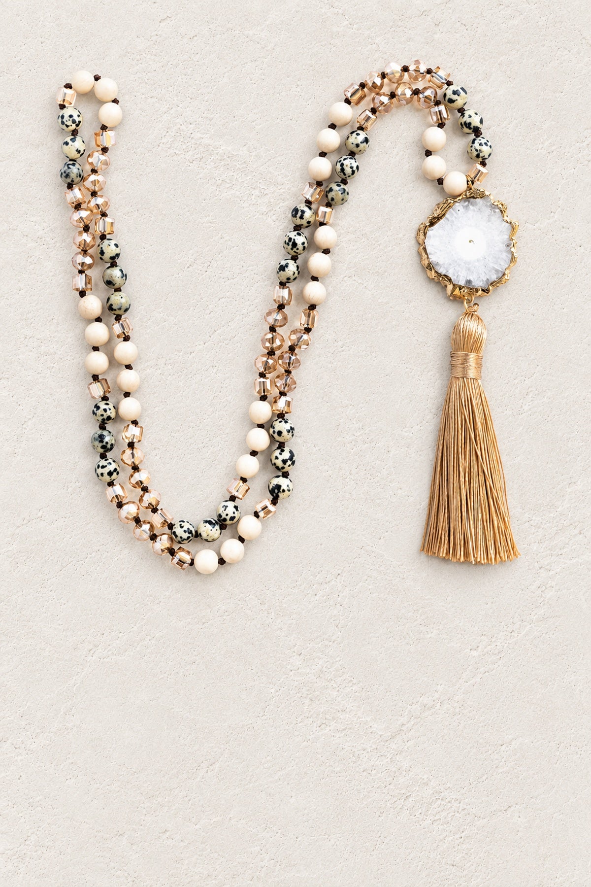 Solar Quartz Agate Slice Tassel Necklace on warm cream plaster background
