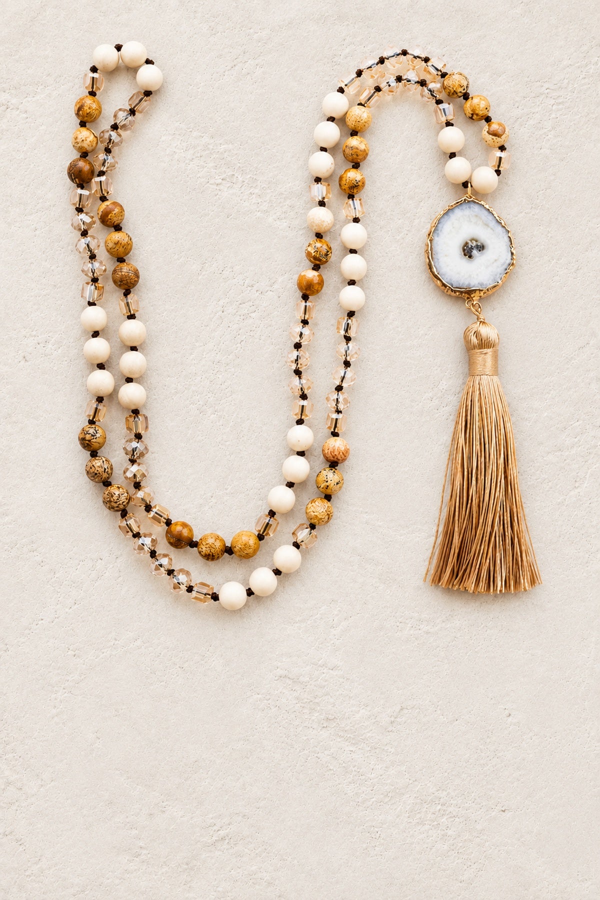 Solar Quartz Agate Slice Tassel Necklace II on warm cream plaster background