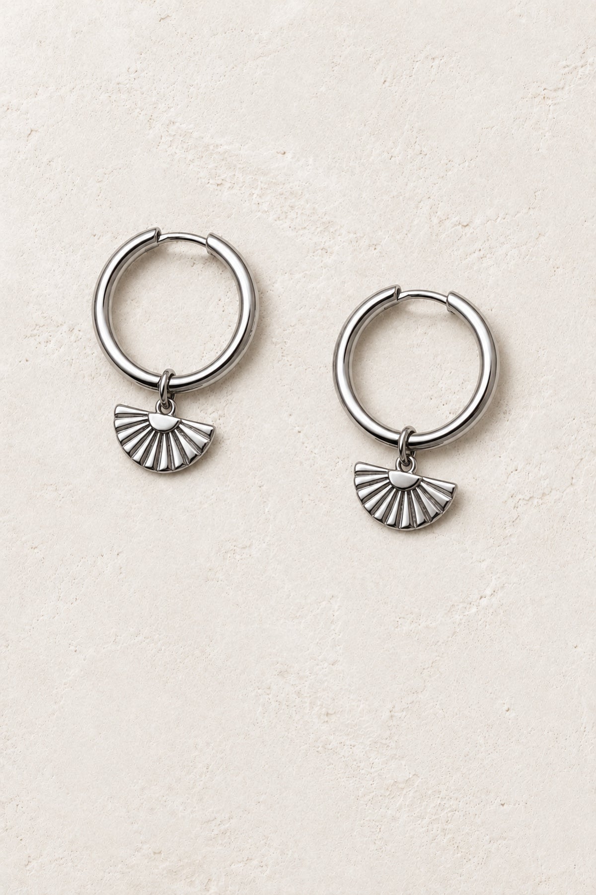 
                  
                    Sora Silver Fan Charm Hoop Earrings - Sterling Silver on warm ivory plaster
                  
                