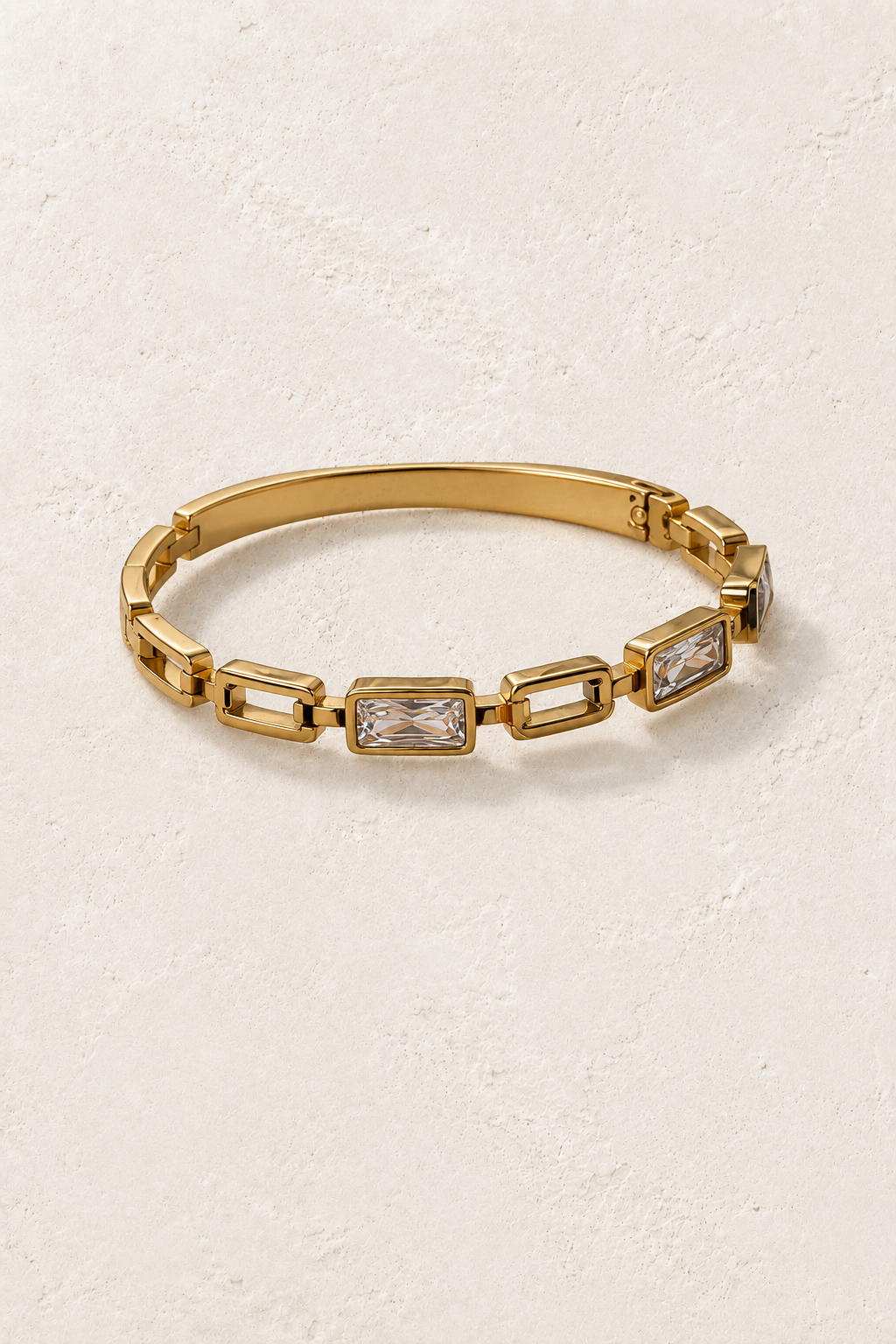 
                  
                    Sorella Gold Rectangular Crystal Link Bangle on cream beige textured background
                  
                