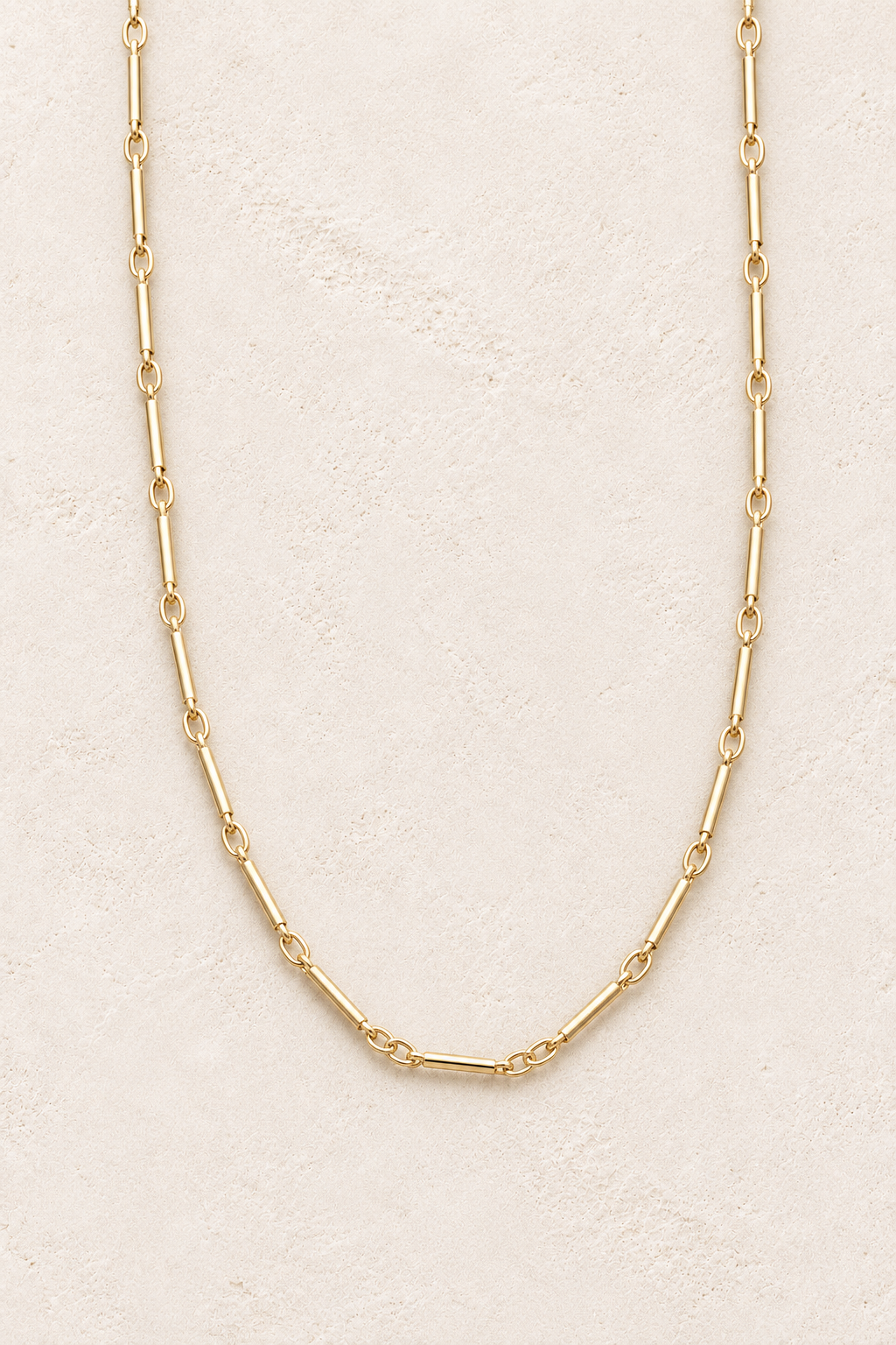
                  
                    Sorella Long Gold Bar Chain Necklace on warm ivory textured background
                  
                