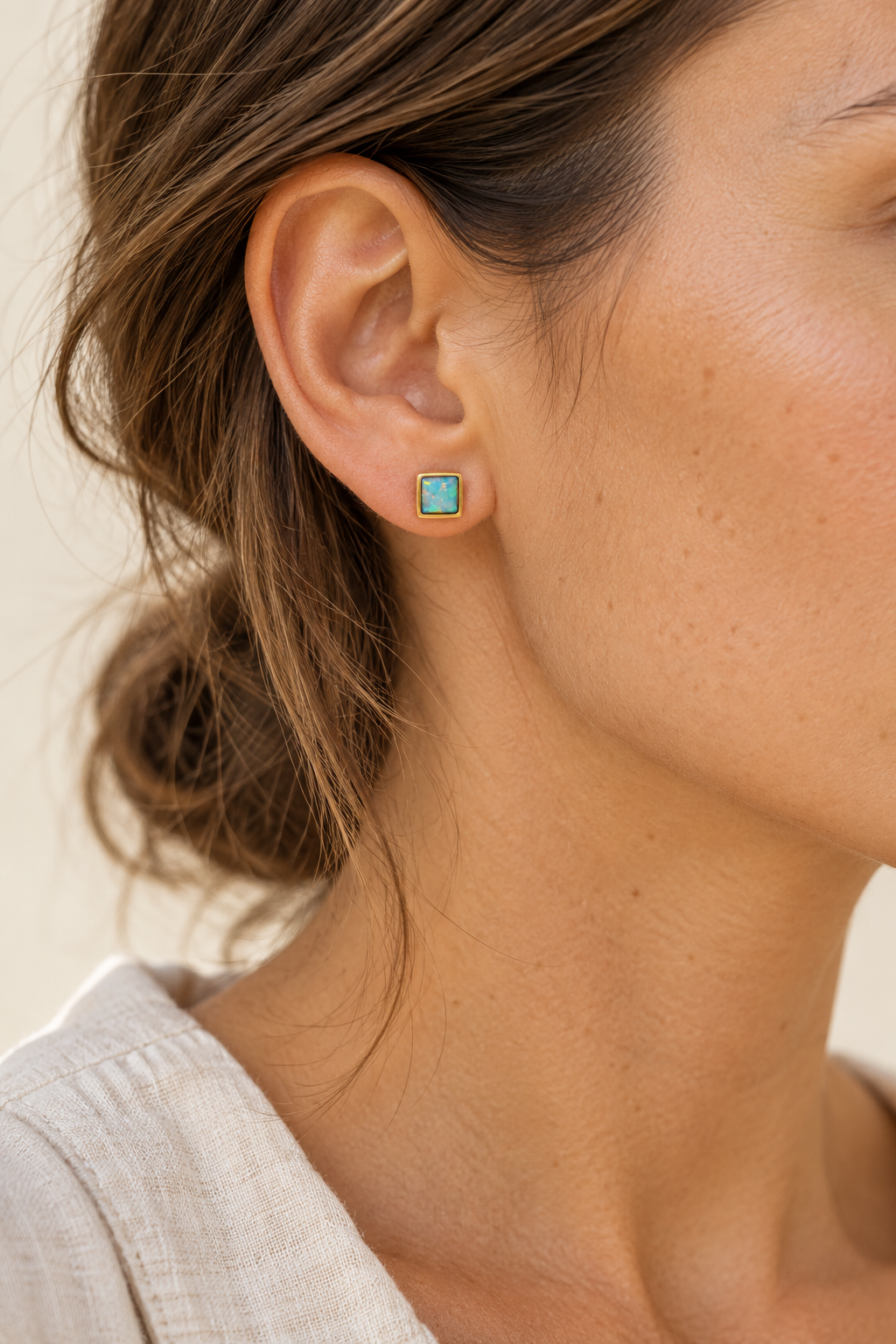 
                  
                    Dainty 6 mm square opal gold stud worn on model
                  
                