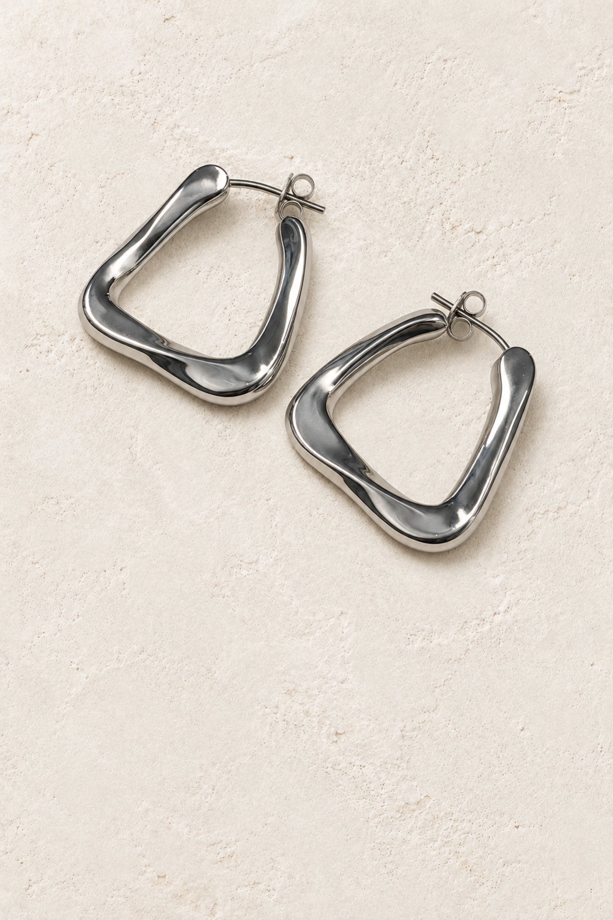 
                  
                    Tavia Silver Organic Triangle Hoop Earrings on warm ivory plaster
                  
                