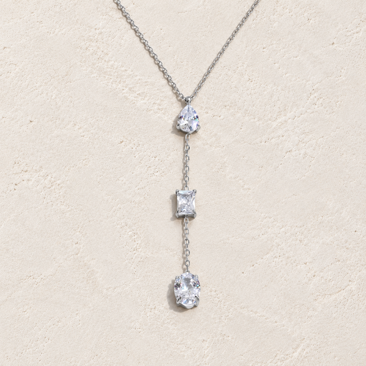 
                  
                    Silver three crystal lariat necklace on cream stone
                  
                