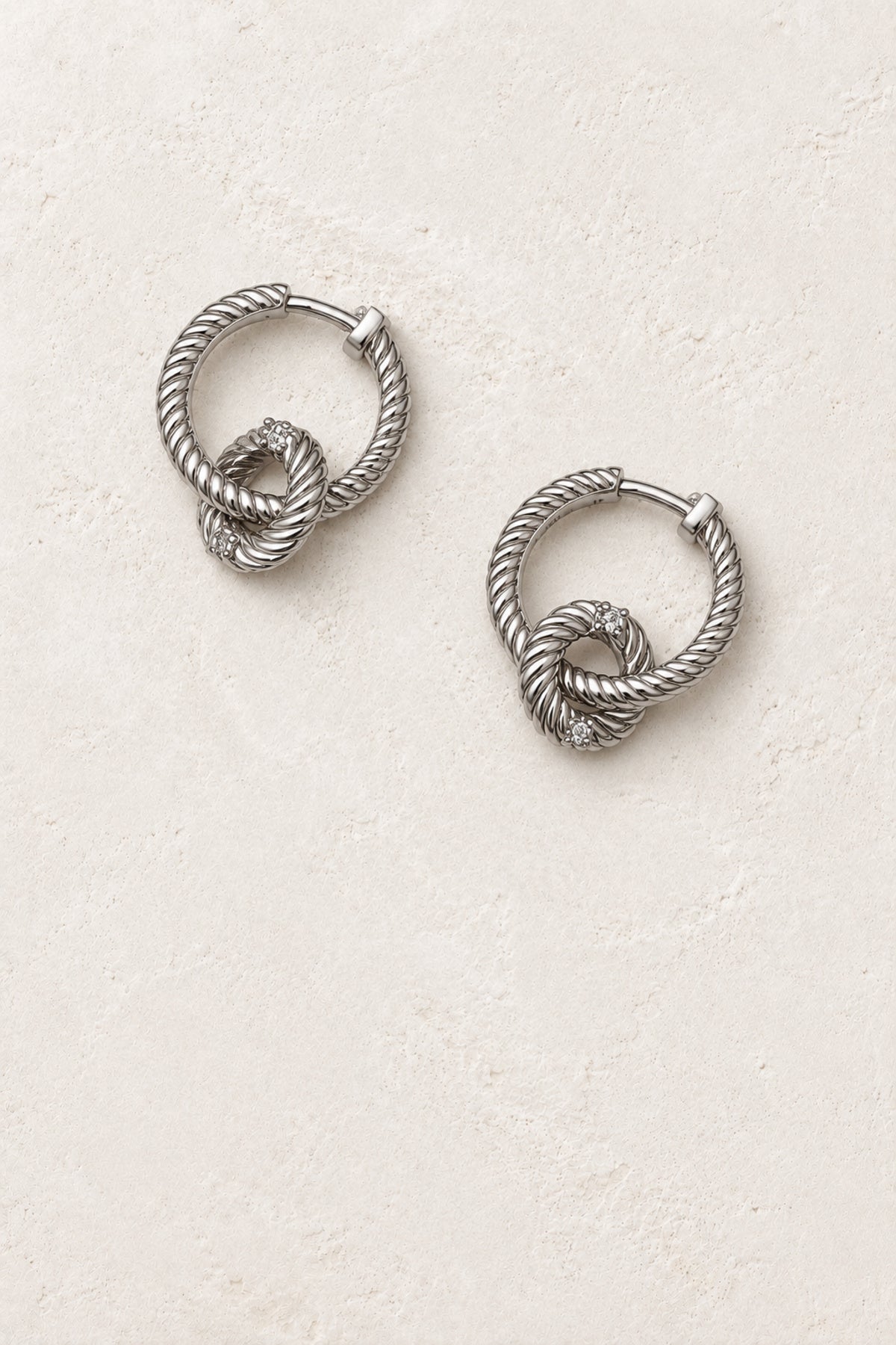 
                  
                    Tindra Silver Twisted Link Hoop Earrings - Sterling Silver on warm ivory plaster
                  
                