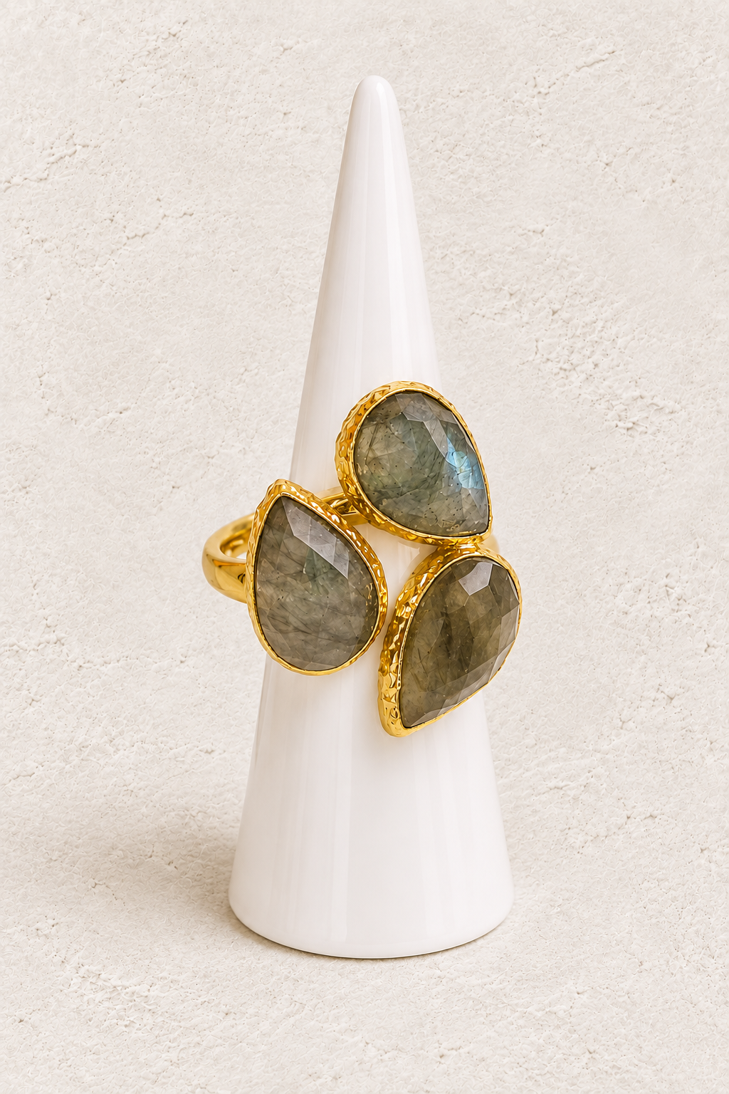 Seraphine Labradorite Ring on white cone against warm textured background